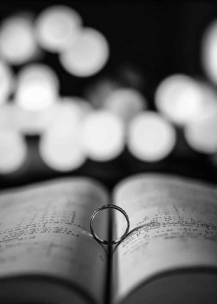 services-02 An artistic black and white photo of a ring on an open book page with bokeh background.